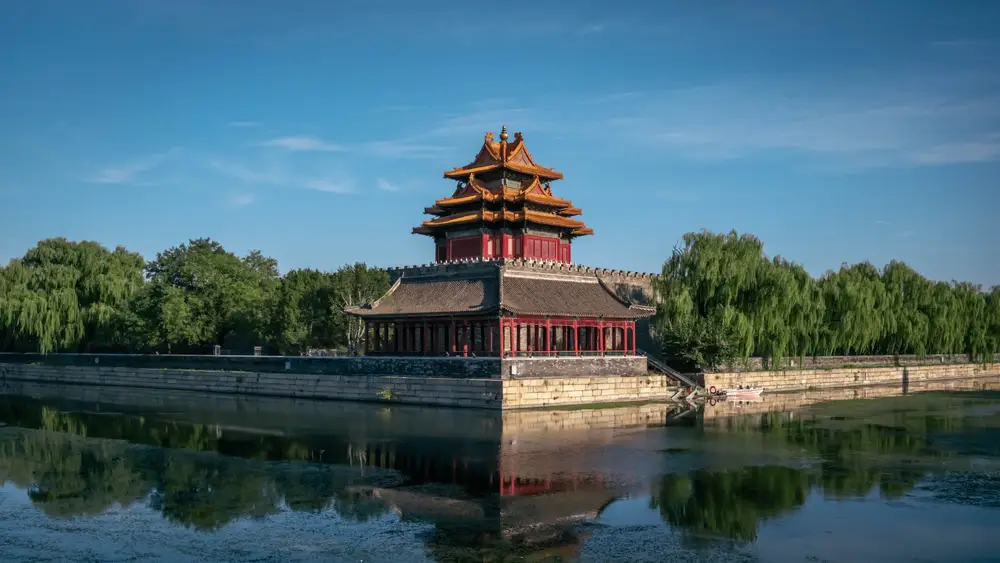 中式角楼临水而立 垂柳环绕晴空下映水面倒影